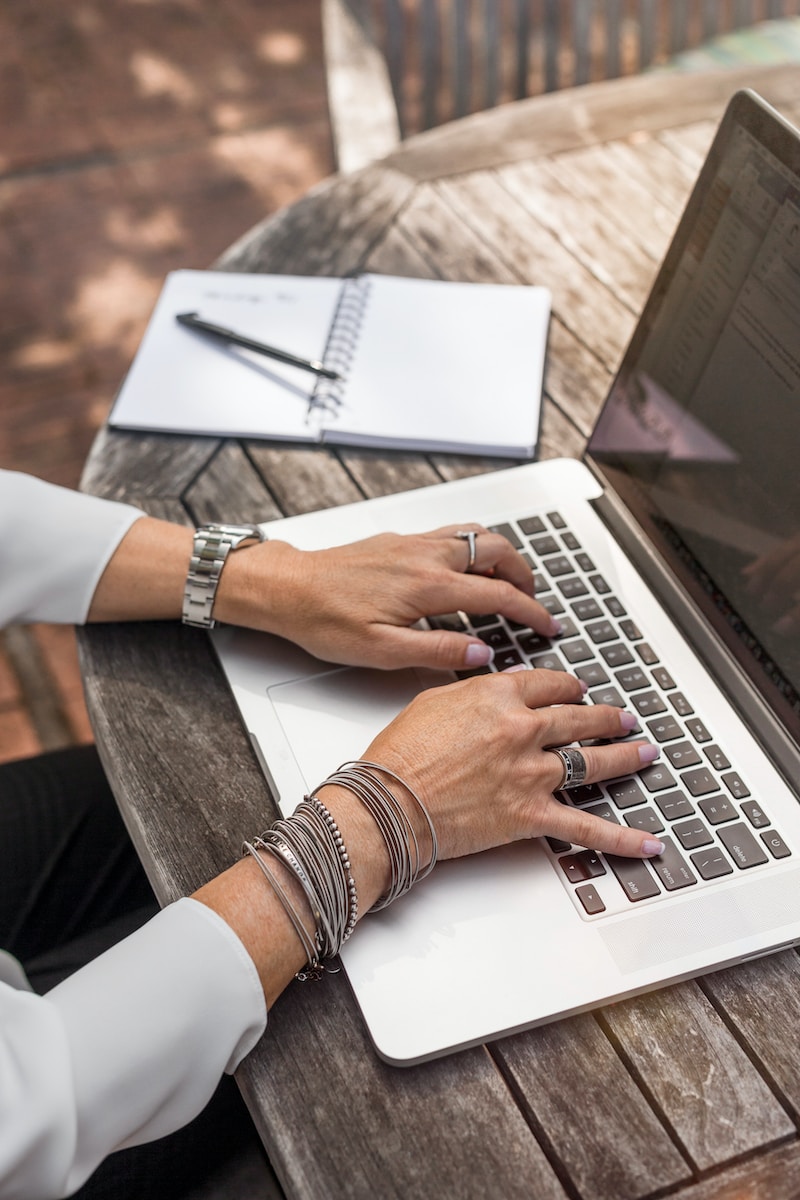 A freelancer offering copywriting services typing on MacBook Pro on brown wooden table during daytime photo